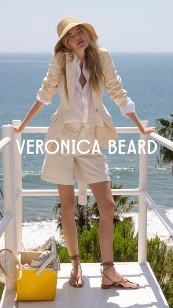 This image showcases Veronica Beard brand apparel with a model leaning against a white railing with the ocean in the bac