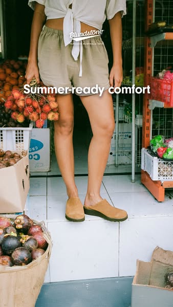 This image ad for Blundstone features a model wearing the brand's mule clog shoes while holding a bunch of rambutan 