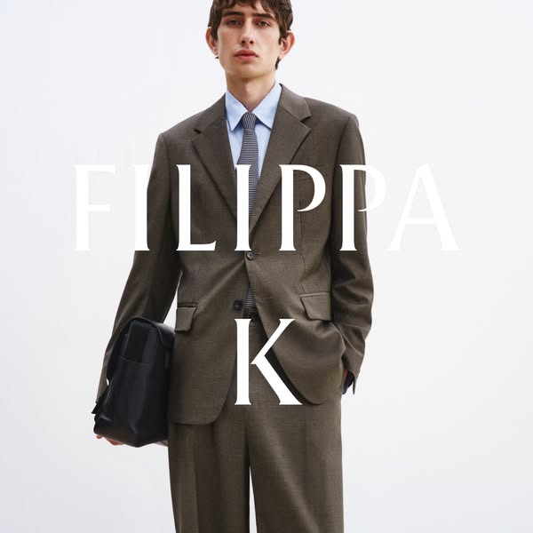 The ad features a single image of a man modeling a FILIPPA K suit and carrying a black bag. The brand name is superimpos