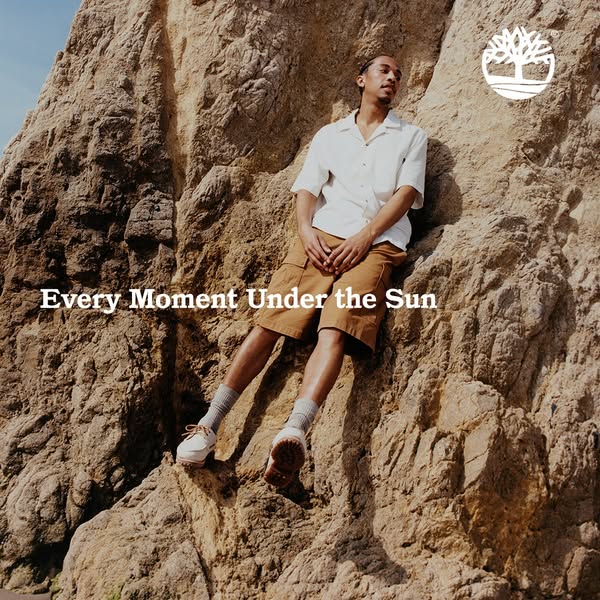 An outdoor lifestyle ad for Timberland shoes featuring a man sitting on a hillside.