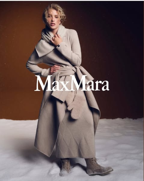 This ad showcases a woman wearing a Max Mara coat, scarf, skirt, mittens, and boots in a snowy setting.