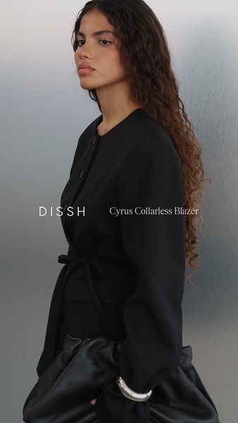 This ad for DISSCH features a woman modeling the Cyrus Collarless Blazer. The ad highlights the blazer's features an