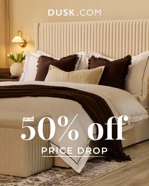 This ad is for Dusk.com, advertising 50% off items due to a price drop. The ad features a bed with multiple pillows and 