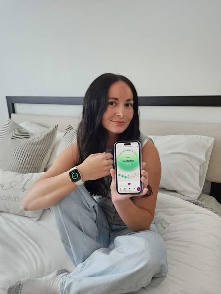 This ad features a woman sitting on a bed, holding up her phone that displays the 'Not Fertile' indication from 