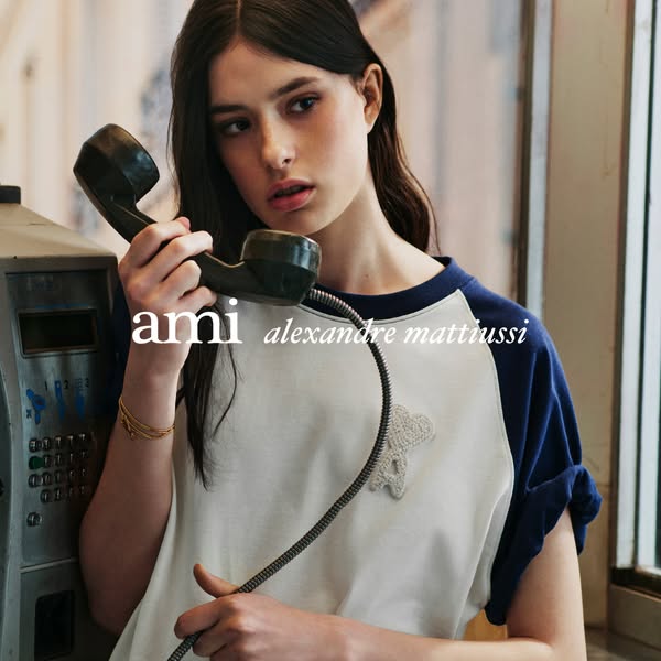 This ad features a young woman in a casual outfit holding a black telephone receiver. The brand "ami alexandre matt