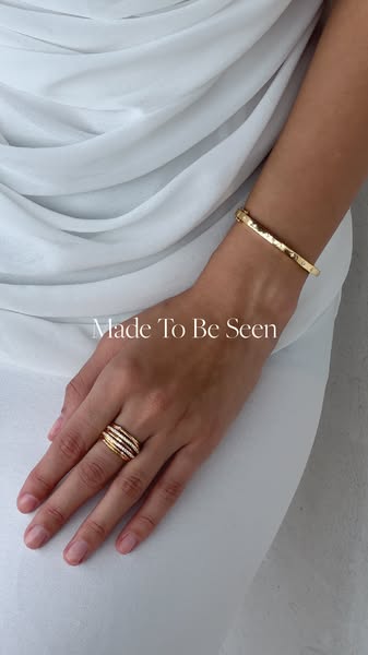 This ad features a person wearing a gold bracelet and layered rings from a jewelry brand.