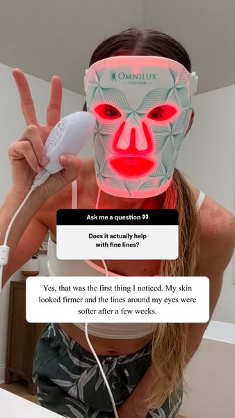 A woman is wearing the Omnilux Contour mask and answering a question about whether it helps with fine lines. She says th