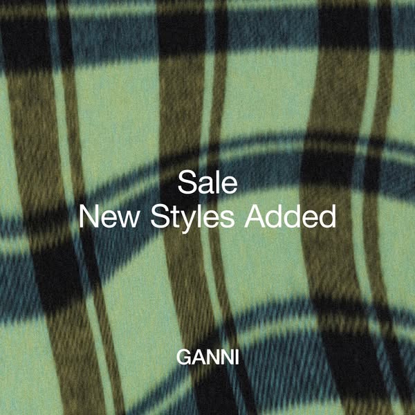 This image ad by GANNI promotes a sale on new styles. The ad features a close-up shot of a plaid fabric, with the text &