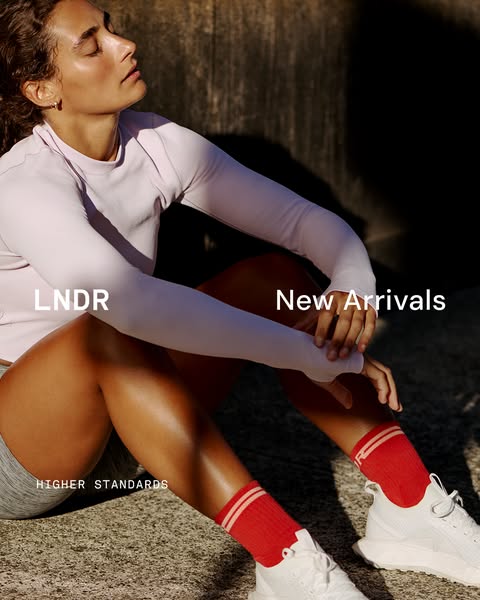 This image ad showcases LNDR's activewear, featuring a woman in a long-sleeved top, running shorts, socks, and sneak