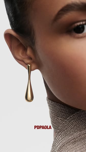 This ad features a close-up shot of a woman wearing a gold teardrop earring from the brand PDPAOLA. The focus is on the 