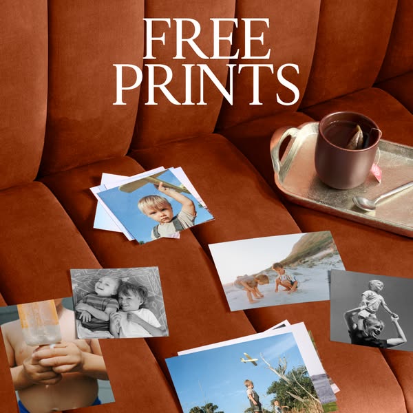 This image ad promotes free prints by showcasing a variety of printed photos scattered on a couch, alongside a cup of te