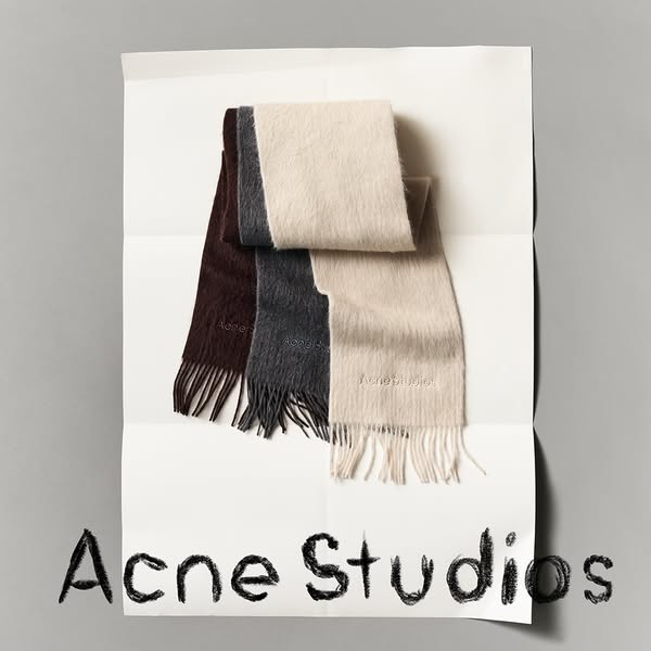 This ad showcases three Acne Studios scarves in different colors, displayed on a white sheet of paper against a gray bac