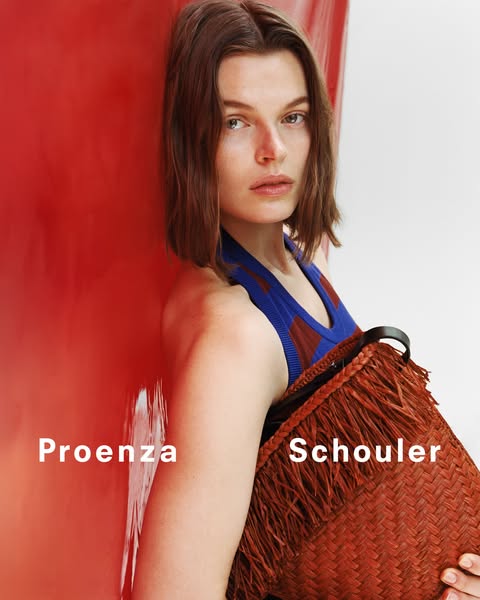 An image ad for Proenza Schouler showing a model against a red backdrop holding a fringed bag.