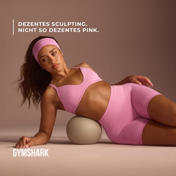This Gymshark ad features a woman wearing a pink seamless athletic outfit, comprised of a sports bra, biker shorts, and 