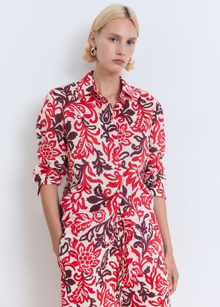 This ad features a woman wearing a red and brown floral print shirt and pants set. The ad focuses on the product itself,