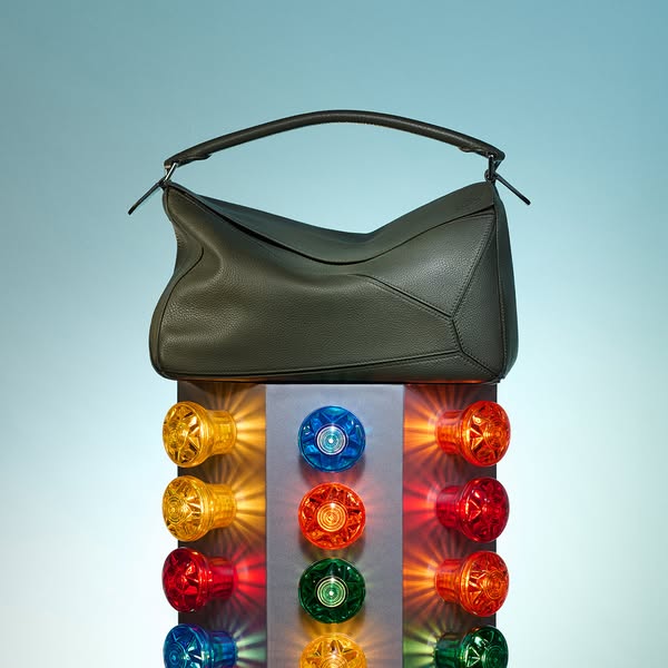 This image ad showcases a green leather handbag placed on top of a light-up display with colorful bulbs. The ad focuses 