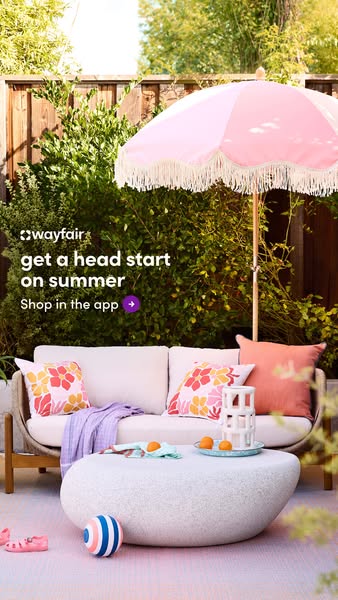 This Wayfair image ad highlights outdoor furniture, specifically a white cushioned couch, a round white stone table, and
