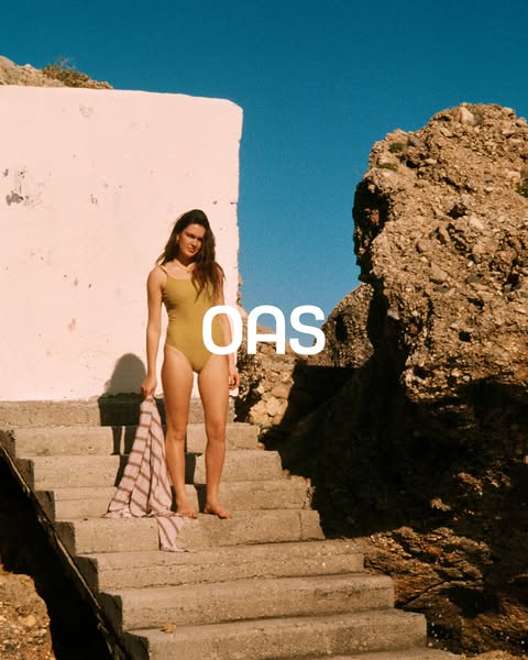 This image ad features a young woman standing on concrete stairs, wearing a one-piece bathing suit and holding a striped