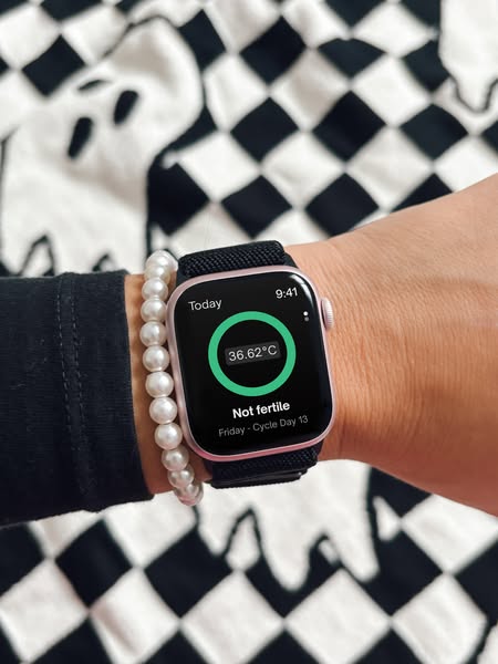 The image shows the basal body temperature displayed on a woman's smart watch, indicating that she is not fertile on