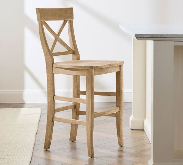 This ad showcases a wooden bar stool with a cross back design, set in a neutral-toned kitchen environment. The focus is 