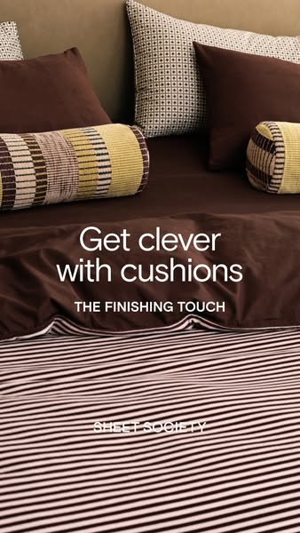 This image ad promotes Sheet Society, showcasing their products, specifically cushions, in a styled bed setting. The ad 