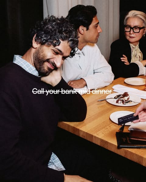 This image ad features three people seated at a dinner table where one person is handing a credit card to an unseen wait