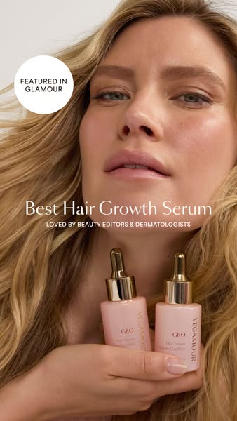 This image ad for Vegamour features a woman with long, wavy blonde hair holding two bottles of Vegamour GRO Hair Serum. 