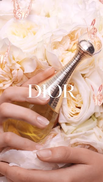 This image ad features Dior's J'adore perfume bottle held gently amidst a bed of white flowers and decorative bu