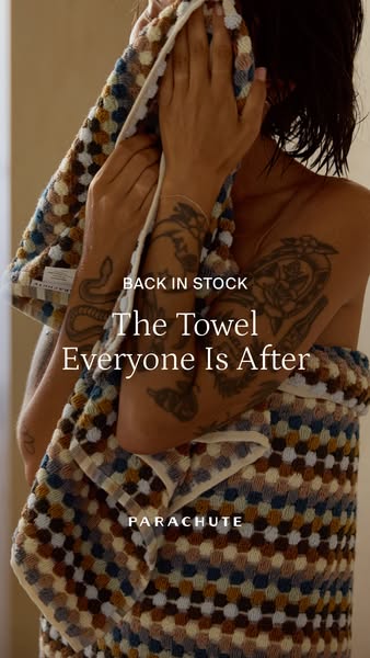 This image ad showcases a Parachute towel that is back in stock and features a person using the towel to dry their face 