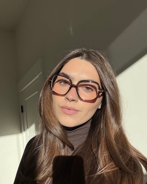 A woman is advertising glasses while the sun shines on her face.