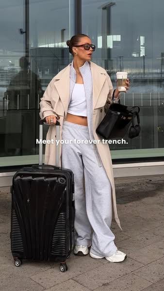 An image ad that promotes a trench coat. The image features a woman in the trench coat pulling a suitcase in what appear