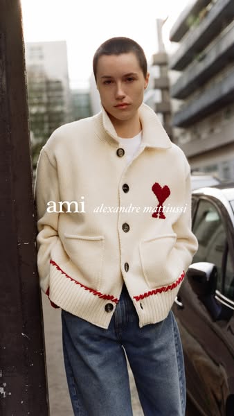 This ad features a person wearing a cream-colored cardigan with a red heart logo. The ad showcases the brand and the car