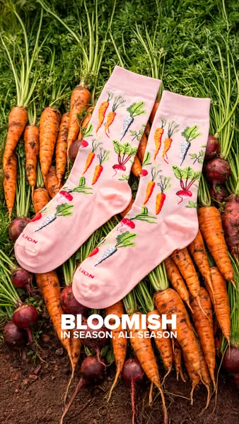The ad features a pair of pink socks with vegetable illustrations displayed on a bed of carrots and beets, with the capt