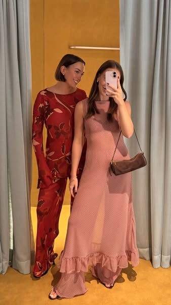 An image ad featuring two women in a store changing room, posing in different outfits in front of a mirror for a phone s