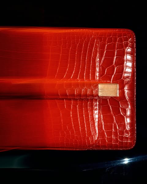 This ad features a luxury red wallet with a reptile skin texture against a dark background.