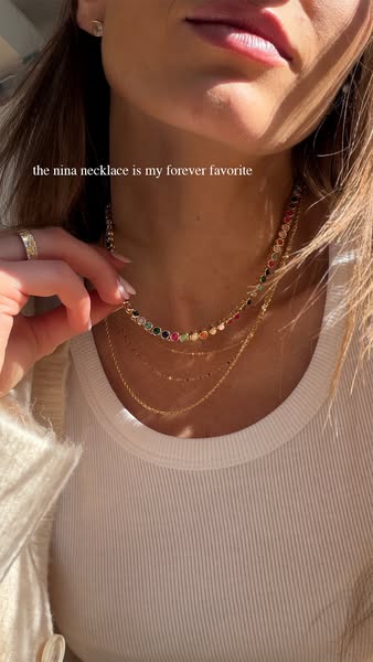 This image ad features a close-up shot of a woman's neck wearing three layered gold necklaces. The top necklace is a