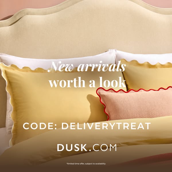 This image ad for DUSK.COM features a close-up of pillows and bedding. It advertises new arrivals and promotes a deliver