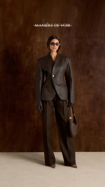 This ad showcases a woman wearing a brown leather suit and carrying a matching handbag from the brand Manière De Voir. T