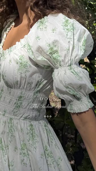 This image ad showcases a DOEN dress called The Ischia Dress on a light-skinned woman wearing the dress outdoors.