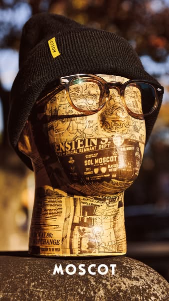 This MOSCOT ad features a mannequin wearing a MOSCOT beanie and eyeglasses against an outdoor setting to display the bra