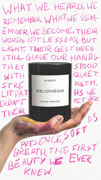This ad features a Byredo candle held in a hand, set against a backdrop of handwritten text in pink. The overall feel is