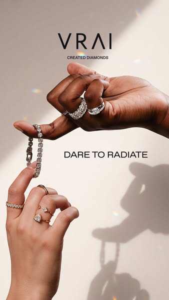 This ad showcases VRAI jewelry. It shows a bracelet held up by a black-skinned hand and rings on both hands. The headlin