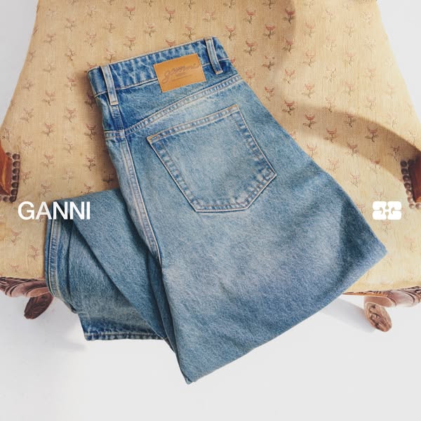 This image ad for GANNI features a pair of light wash jeans artfully draped over an antique chair, emphasizing the brand