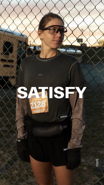 An image ad for Satisfy brand activewear featuring a runner in an outdoor setting.