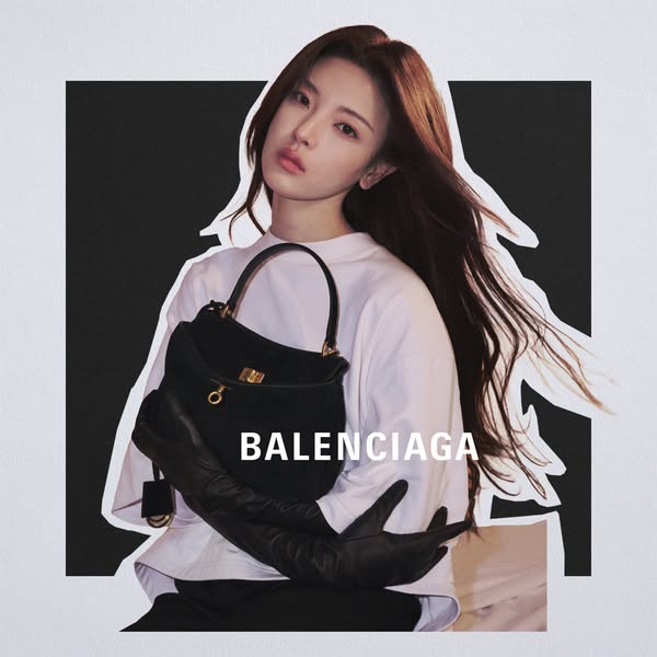 The ad showcases a woman holding a black Balenciaga handbag, emphasizing luxury and high fashion through a cutout design