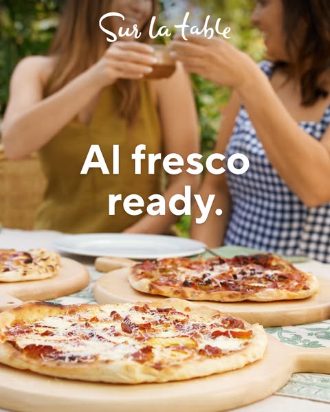 This ad for Sur la table shows a group of friends enjoying pizzas from Sur la table on pizza boards outdoors, implying t