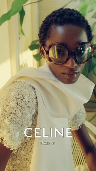 An ad for CELINE featuring a person in an off-white dress and oversized, round sunglasses. The CELINE logo is displayed 