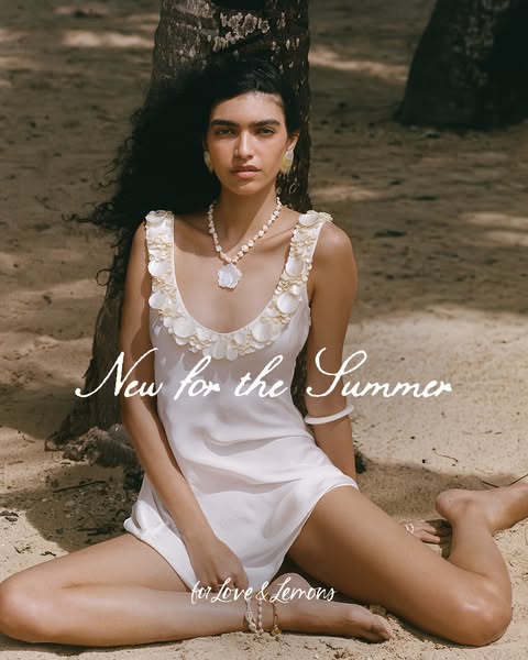 This ad for for Love & Lemons features a woman on a beach modeling a seashell-themed dress, necklace, and earrings.