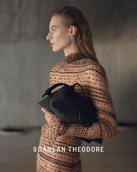 A poised model showcases a Scanlan Theodore handbag against a blurred concrete background.