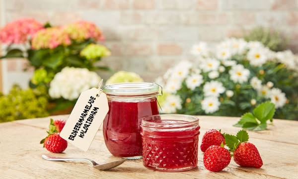 This image ad showcases two jars of strawberry jam with a focus on being low calorie, along with fresh strawberries scat